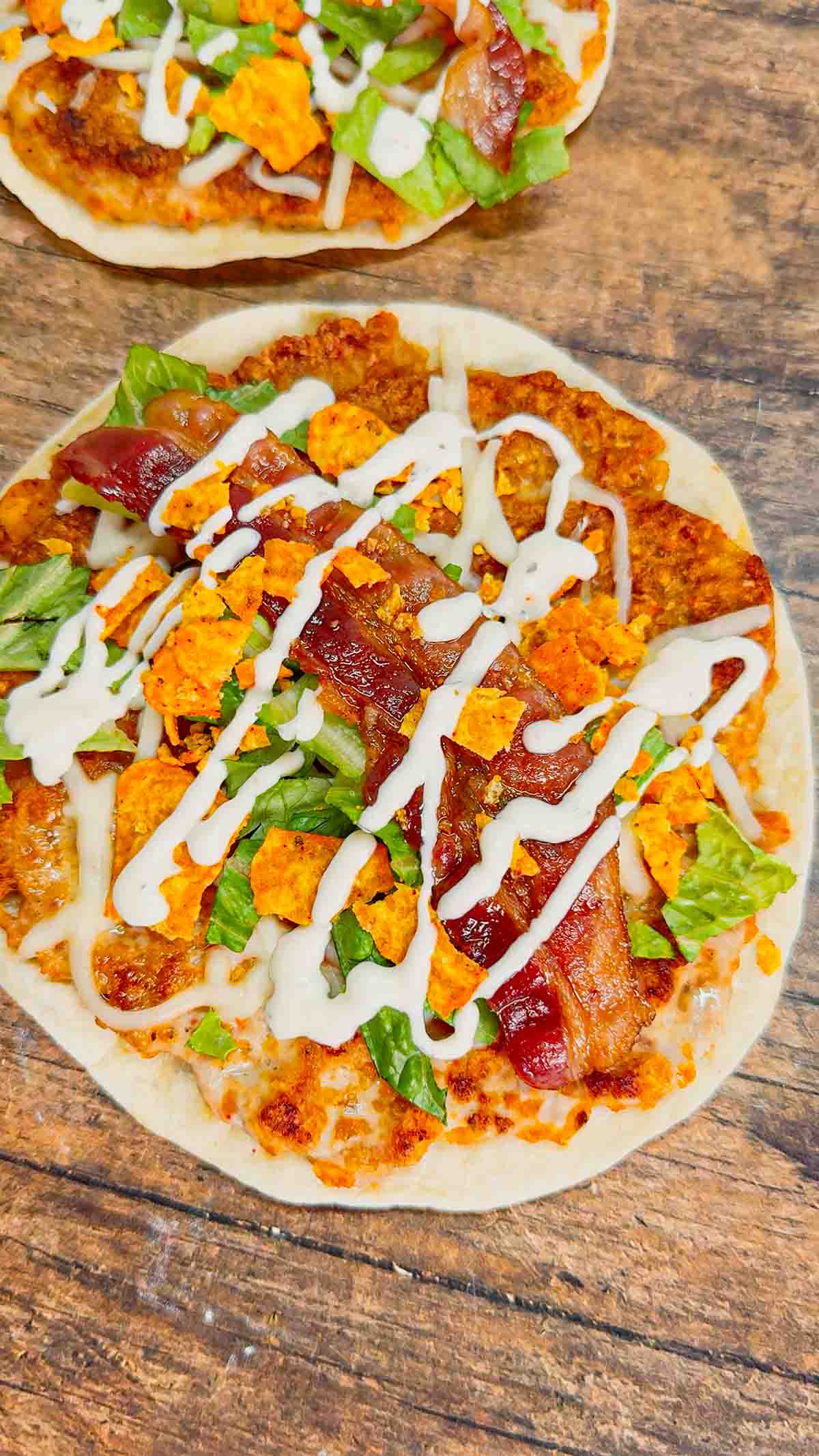 Doritos Crusted Chicken Smash Tacos are a fun twist on smash burger tacos. Flour tortillas are spread with a ground chicken and crushed Doritos mixture and fried until crispy before being topped with shredded mozzarella, chopped lettuce, crispy bacon, ranch dressing and more Doritos.