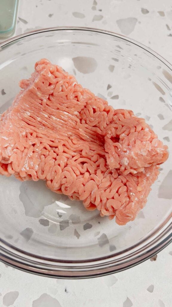 raw ground chicken in a glass mixing bowl