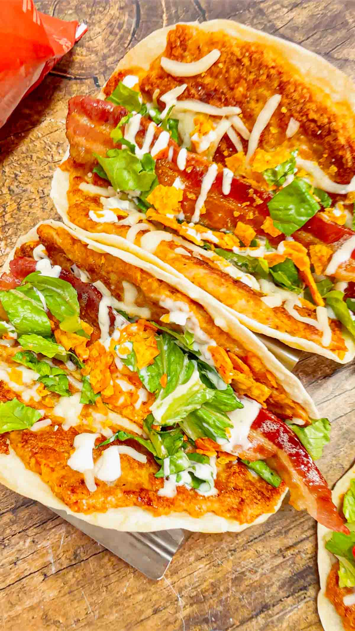 Doritos Crusted Chicken Smash Tacos are a fun twist on smash burger tacos. Flour tortillas are spread with a ground chicken and crushed Doritos mixture and fried until crispy before being topped with shredded mozzarella, chopped lettuce, crispy bacon, ranch dressing and more Doritos.