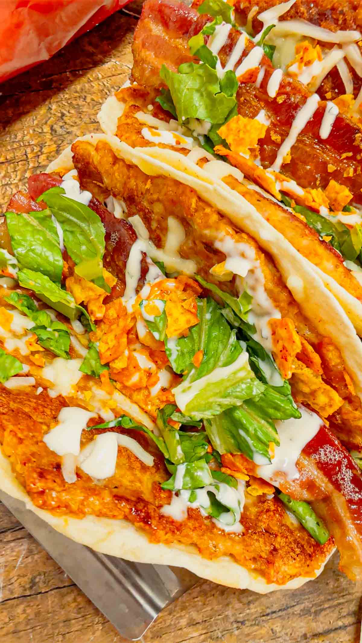 Doritos Crusted Chicken Smash Tacos are a fun twist on smash burger tacos. Flour tortillas are spread with a ground chicken and crushed Doritos mixture and fried until crispy before being topped with shredded mozzarella, chopped lettuce, crispy bacon, ranch dressing and more Doritos.