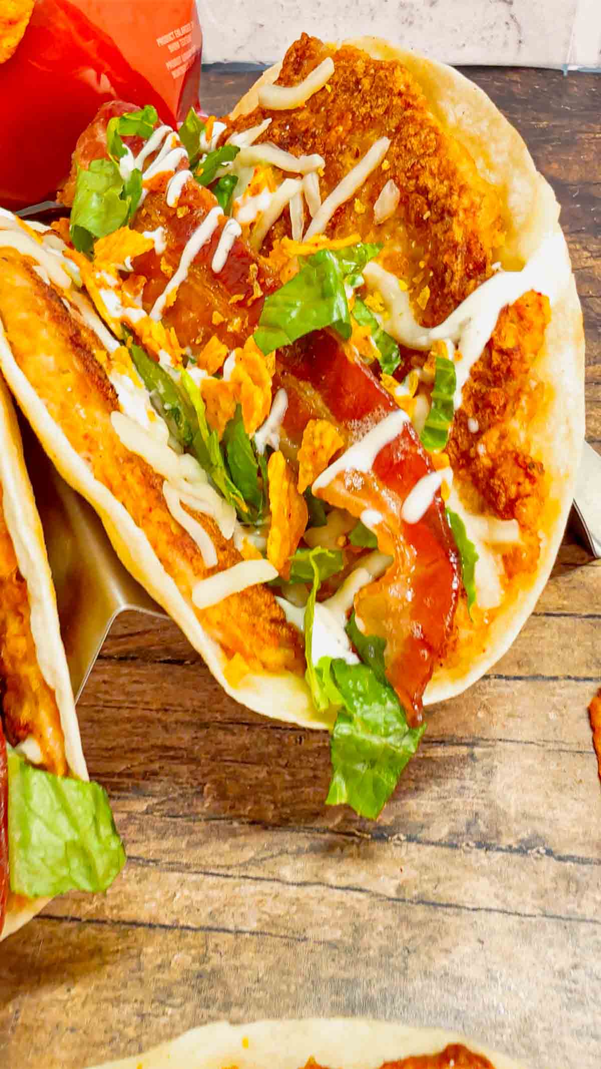 Doritos Crusted Chicken Smash Tacos are a fun twist on smash burger tacos. Flour tortillas are spread with a ground chicken and crushed Doritos mixture and fried until crispy before being topped with shredded mozzarella, chopped lettuce, crispy bacon, ranch dressing and more Doritos.