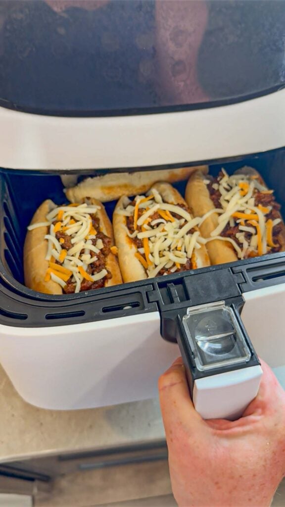sloppy joe dogs in an air fryer basket before cooking