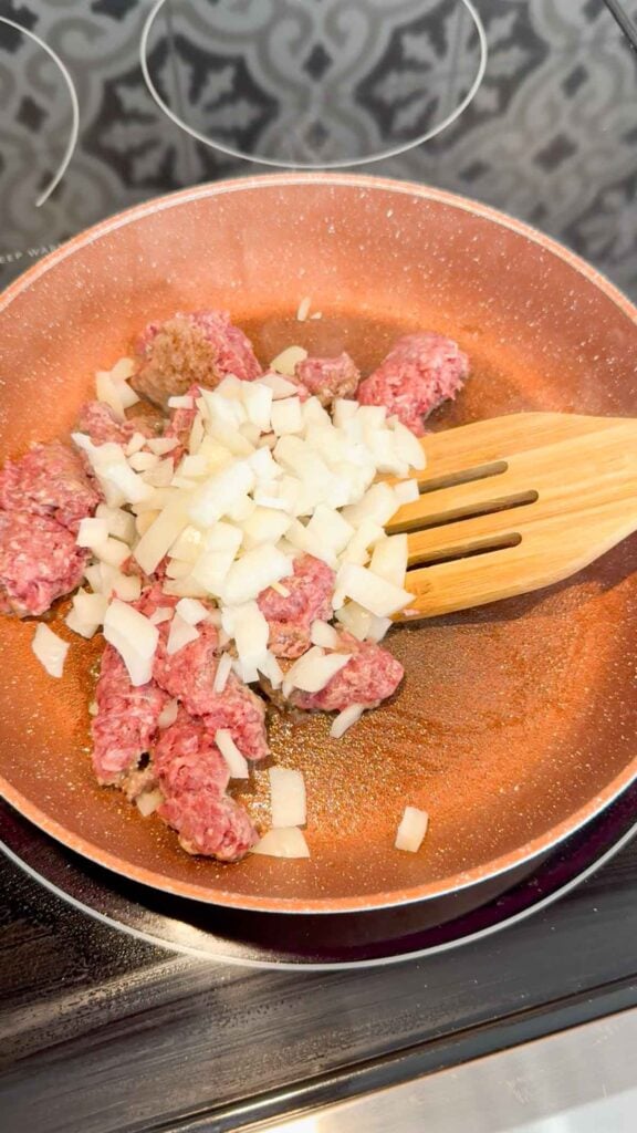 chopped onions added to a skillet with ground beef