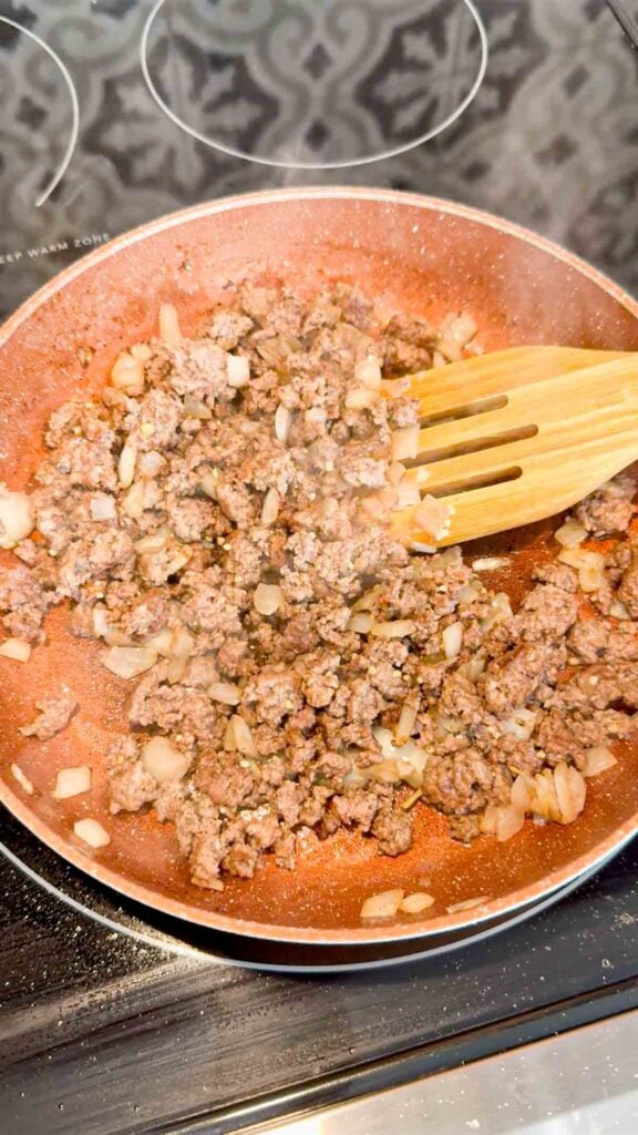cooked ground beef and diced onions in a skillet