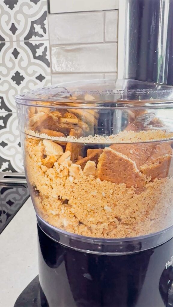 golden Oreos and graham crackers being blended in a food processor
