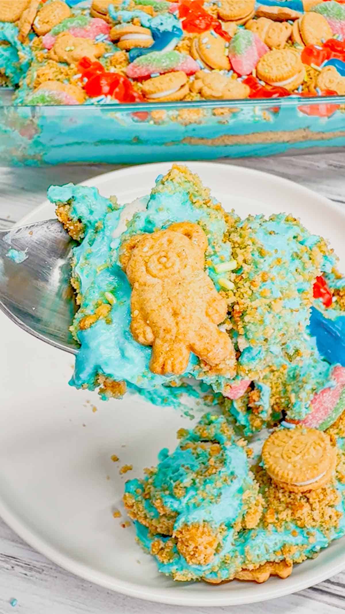 Summer Dirt Cake is an easy no bake dessert recipe perfect for parties and potlucks. This beach themed dirt cake is made with golden Oreo and graham cracker crumbs, layered with a delicious cream cheese and vanilla pudding mixture and all topped with mini cookies and beach themed gummy candies.