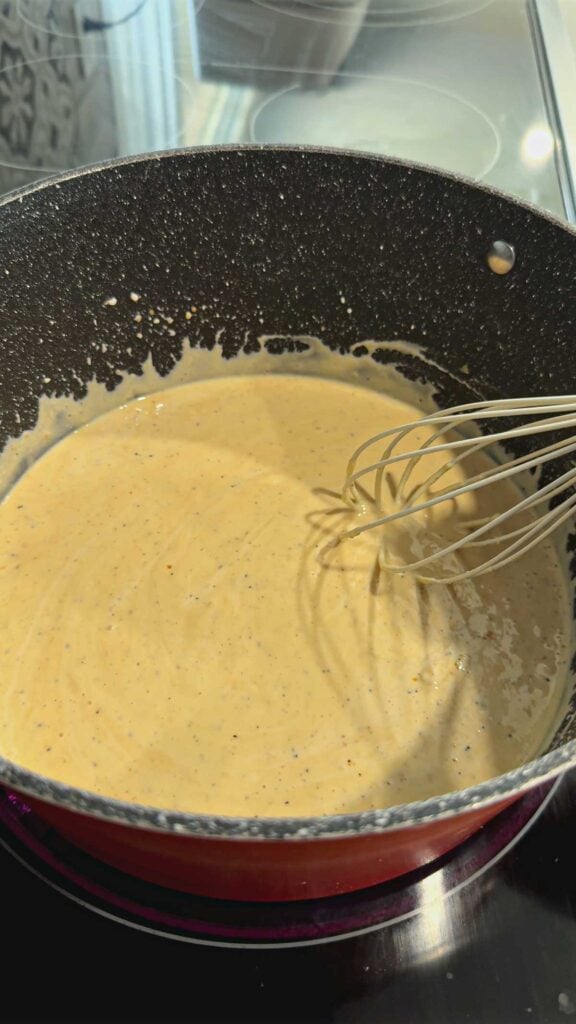 stirring mac and cheese sauce in a pot