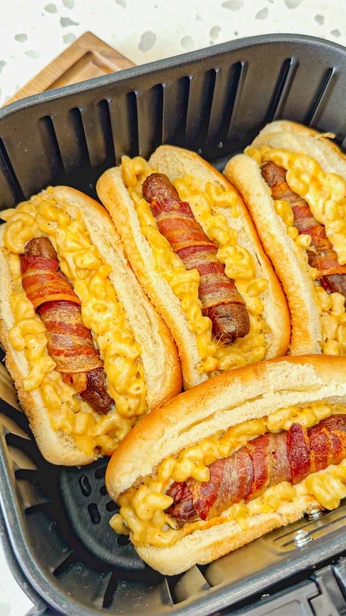 Air Fryer Bacon Wrapped Mac and Cheese Dogs are a fun and easy dinner the whole family will love. The bacon wrapped wieners are air fried until crispy and then placed on buns loaded with creamy mac and cheese and toasted to perfection.