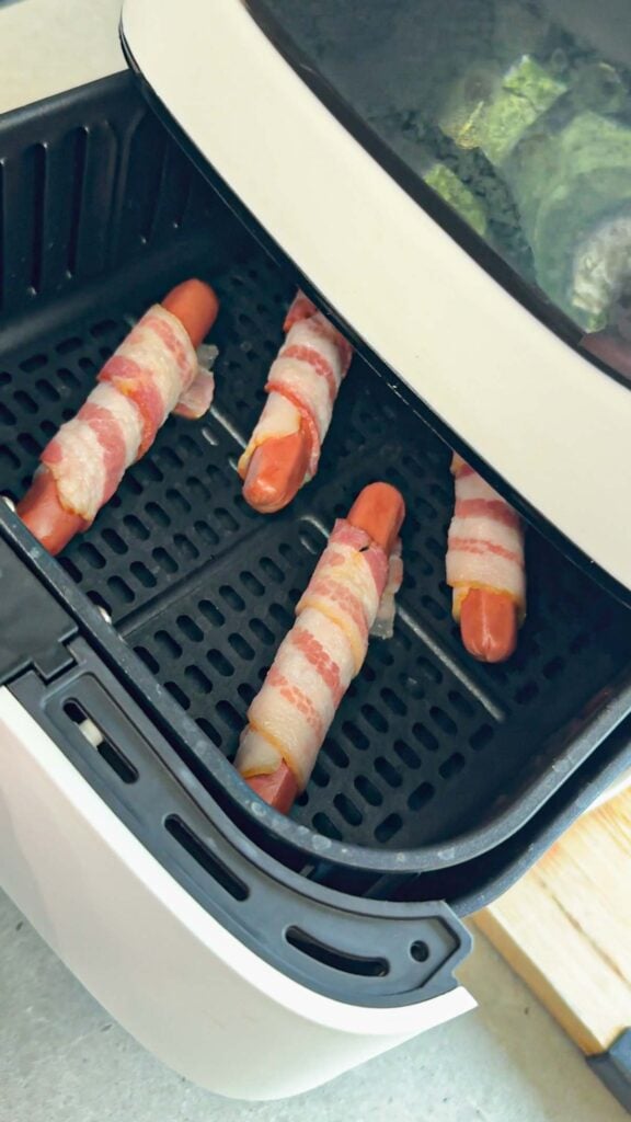 bacon wrapped wieners going in to the air fryer to cook