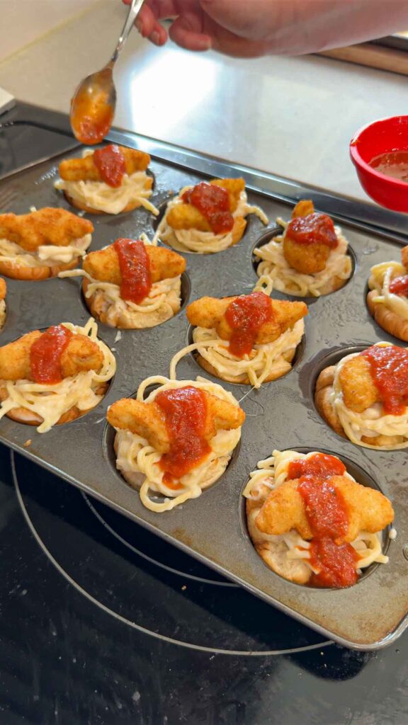 marinara sauce spooned over dino nuggets and spaghetti alfredo in garlic bread cups