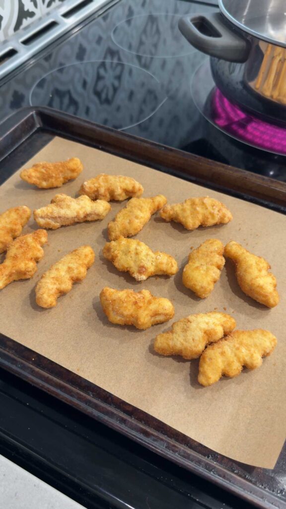 dino nuggets on a parchment lined baking sheet