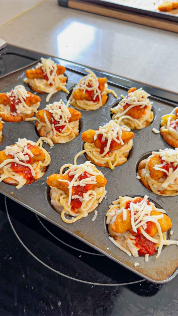 shredded cheese and marinara on top of dino nuggets and spaghetti alfredo