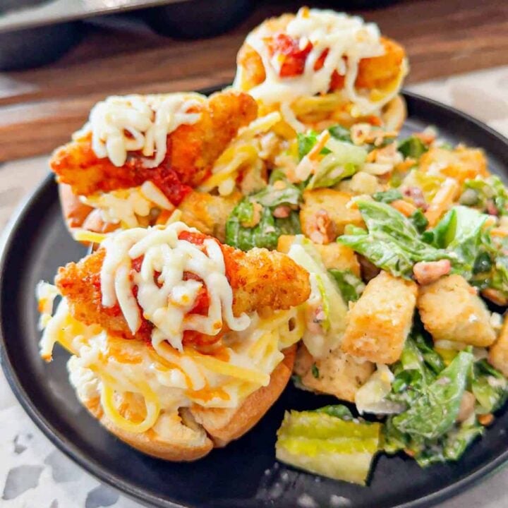 Dino Nugget Chicken Parm Cups are a fun and easy muffin tin dinner the whole family will love. Hamburger buns are spread with garlic butter, baked in muffin tins and stuffed with creamy alfredo spaghetti and topped with dino nuggets, marinara and mozzarella.