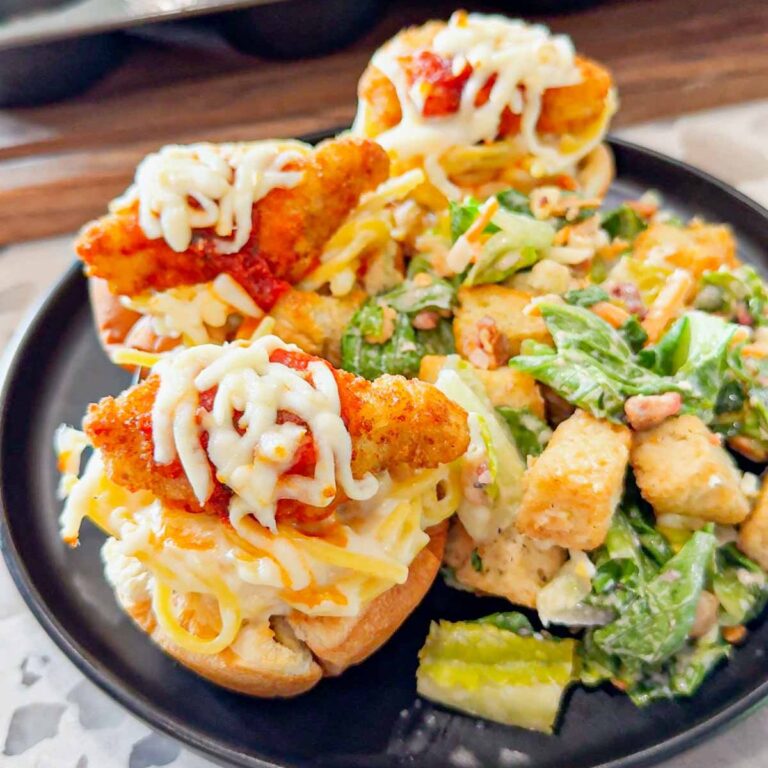 Dino Nugget Chicken Parm Cups are a fun and easy muffin tin dinner the whole family will love. Hamburger buns are spread with garlic butter, baked in muffin tins and stuffed with creamy alfredo spaghetti and topped with dino nuggets, marinara and mozzarella.