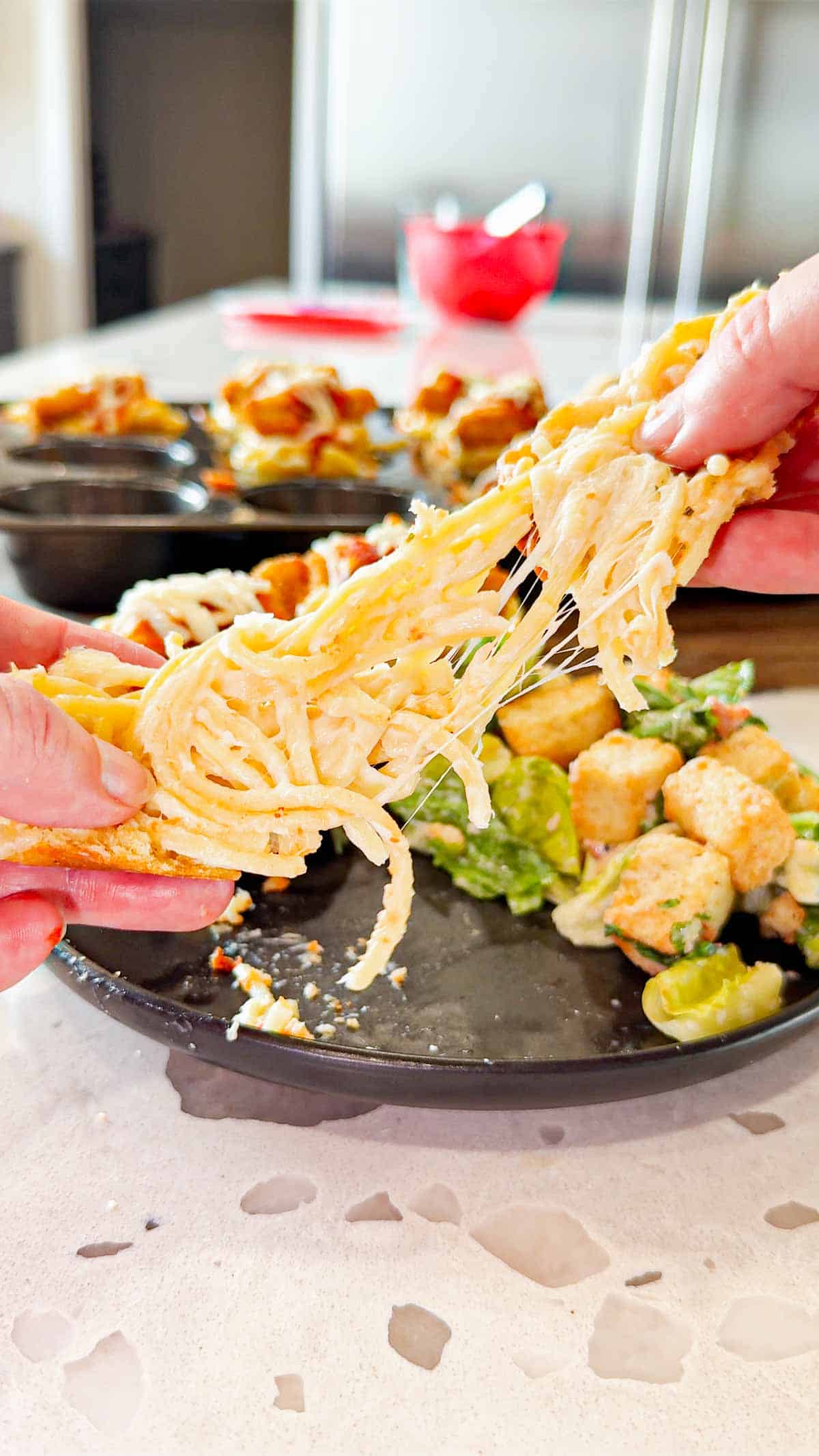 Dino Nugget Chicken Parm Cups are a fun and easy muffin tin dinner the whole family will love. Hamburger buns are spread with garlic butter, baked in muffin tins and stuffed with creamy alfredo spaghetti and topped with dino nuggets, marinara and mozzarella.