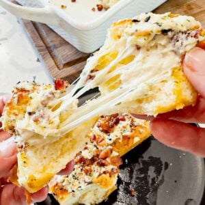 Everything Bacon Cheesy Hawaiian Roll Garlic Bread is the perfect party food or dinner side dish. King's Hawaiian Rolls are sliced and stuffed with herb and garlic cream cheese, crumbled bacon and shredded mozzarella cheese, brushed with garlic butter and topped with everything bagel seasoning before being baked to melty perfection.