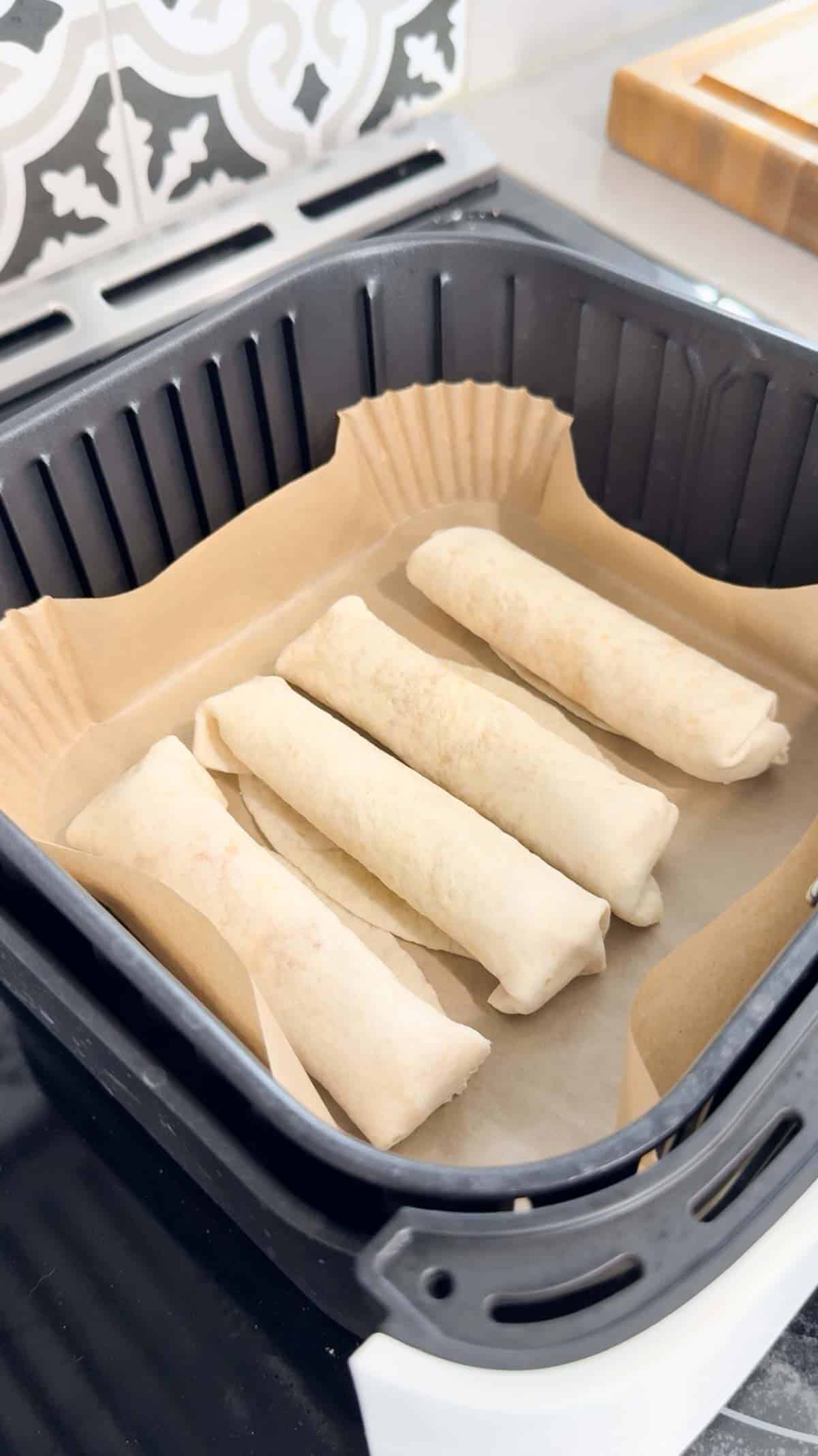 ham and cheese tortilla roll ups in an air fryer basket
