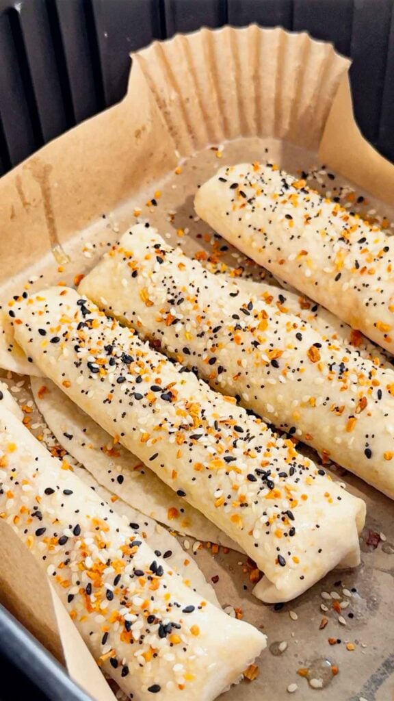 cheese and ham stuffed tortillas topped with everything bagel seasoning in an air fryer basket