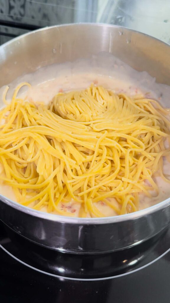 cooked linguine noodles added to pot with alfredo sauce