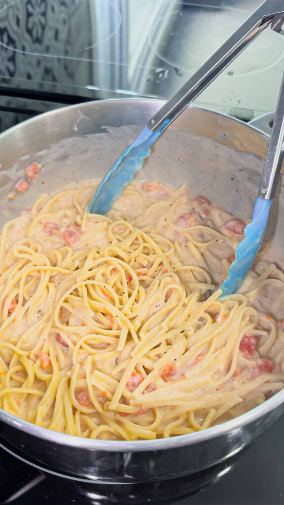 stirring linguine alfredo and rotel in a pot