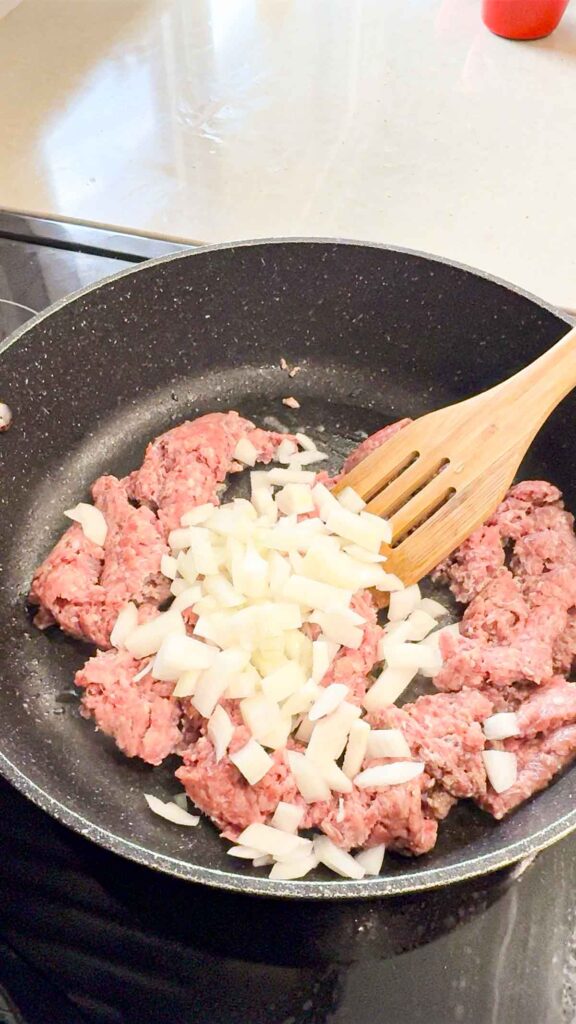 diced onions added to skillet with raw ground beef