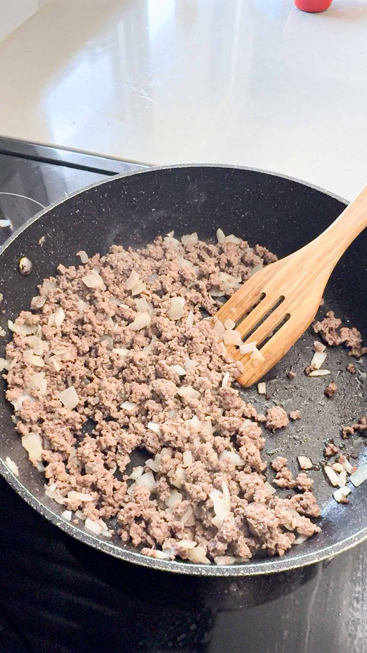 cooked ground beef and diced onions in a skillet