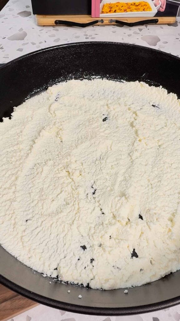 ricotta spread in the bottom of a cast iron skillet
