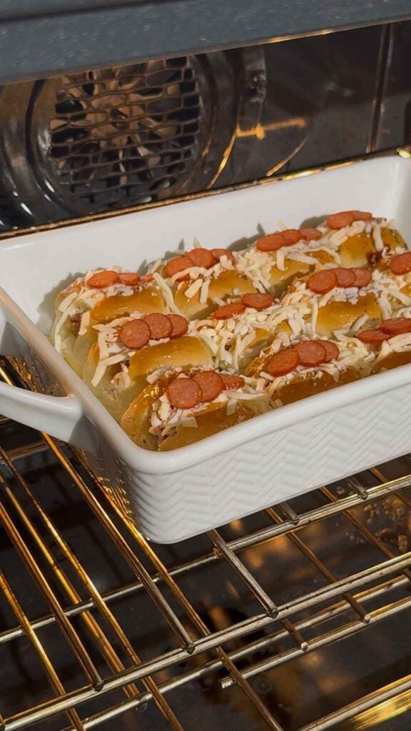 mini pizza dog sliders in a baking dish in the oven