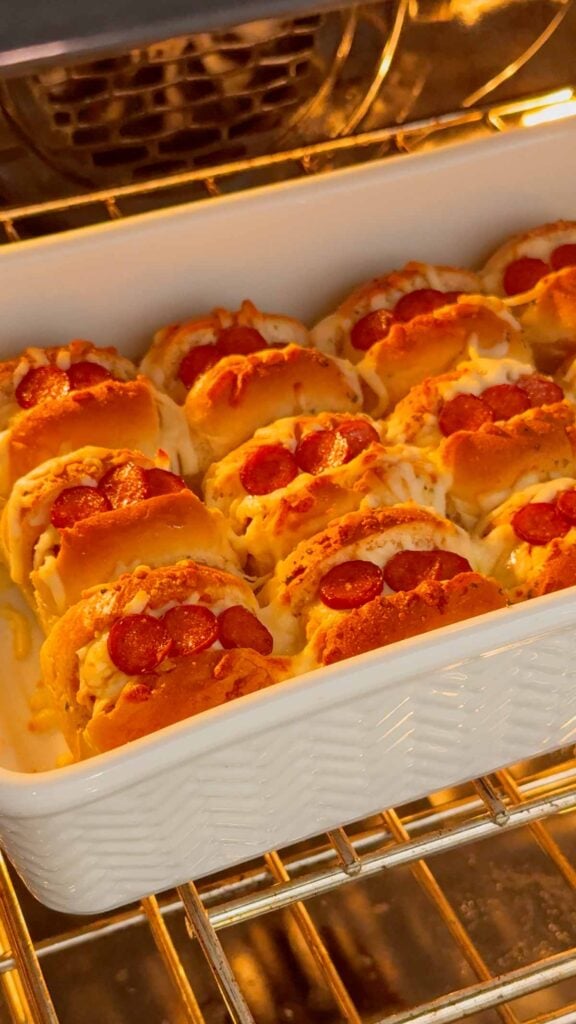 mini pizza dog sliders in a dish baking in the oven