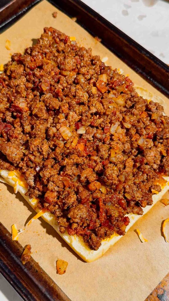 bbq ground beef mixture on slider buns on a baking sheet