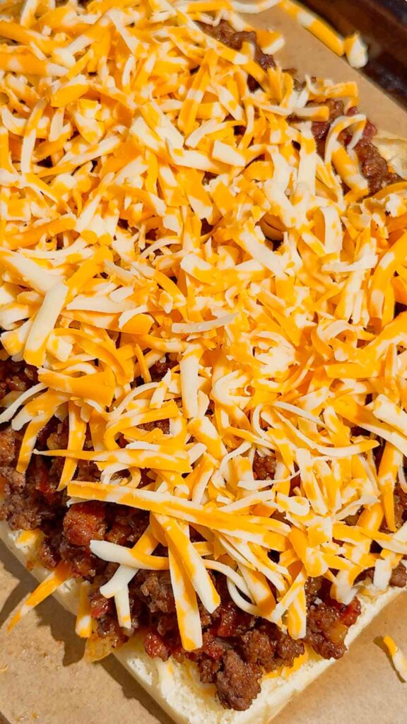 shredded cheddar cheese on top of ground beef mixture on slider buns