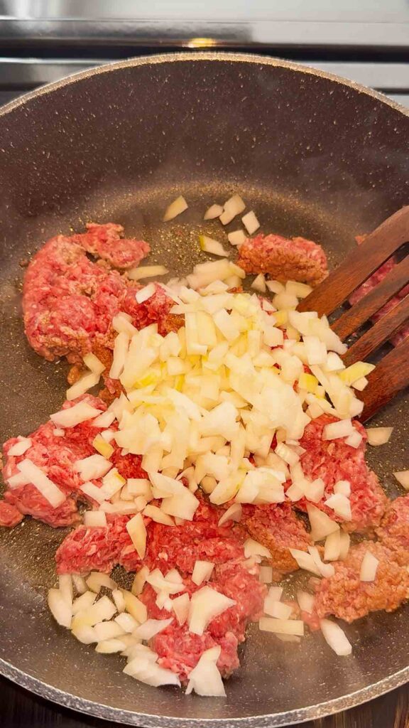 diced onions added to skillet with raw ground beef