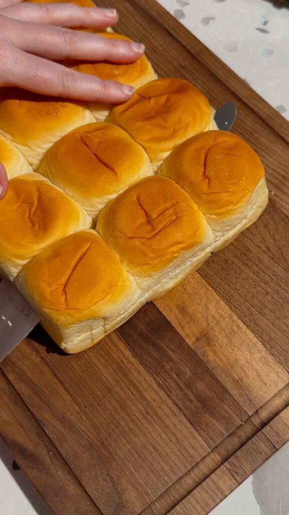 slicing open kings hawaiian rolls on a cutting board