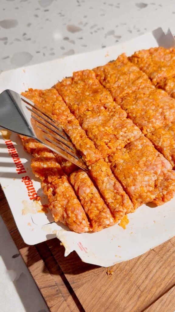 using a spatula to make rib lines in the pork patties