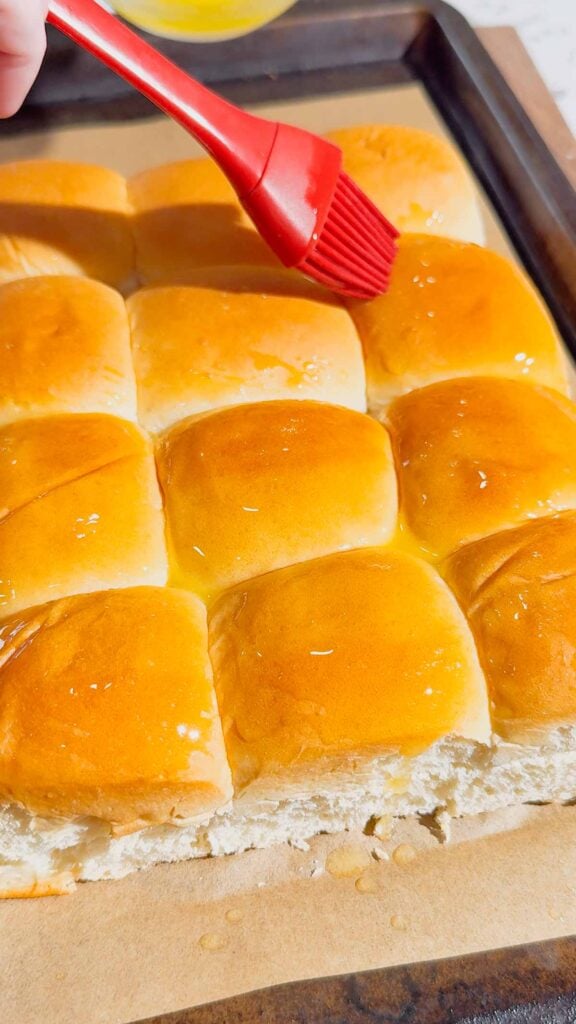 brushing butter on top of king's hawaiian rolls
