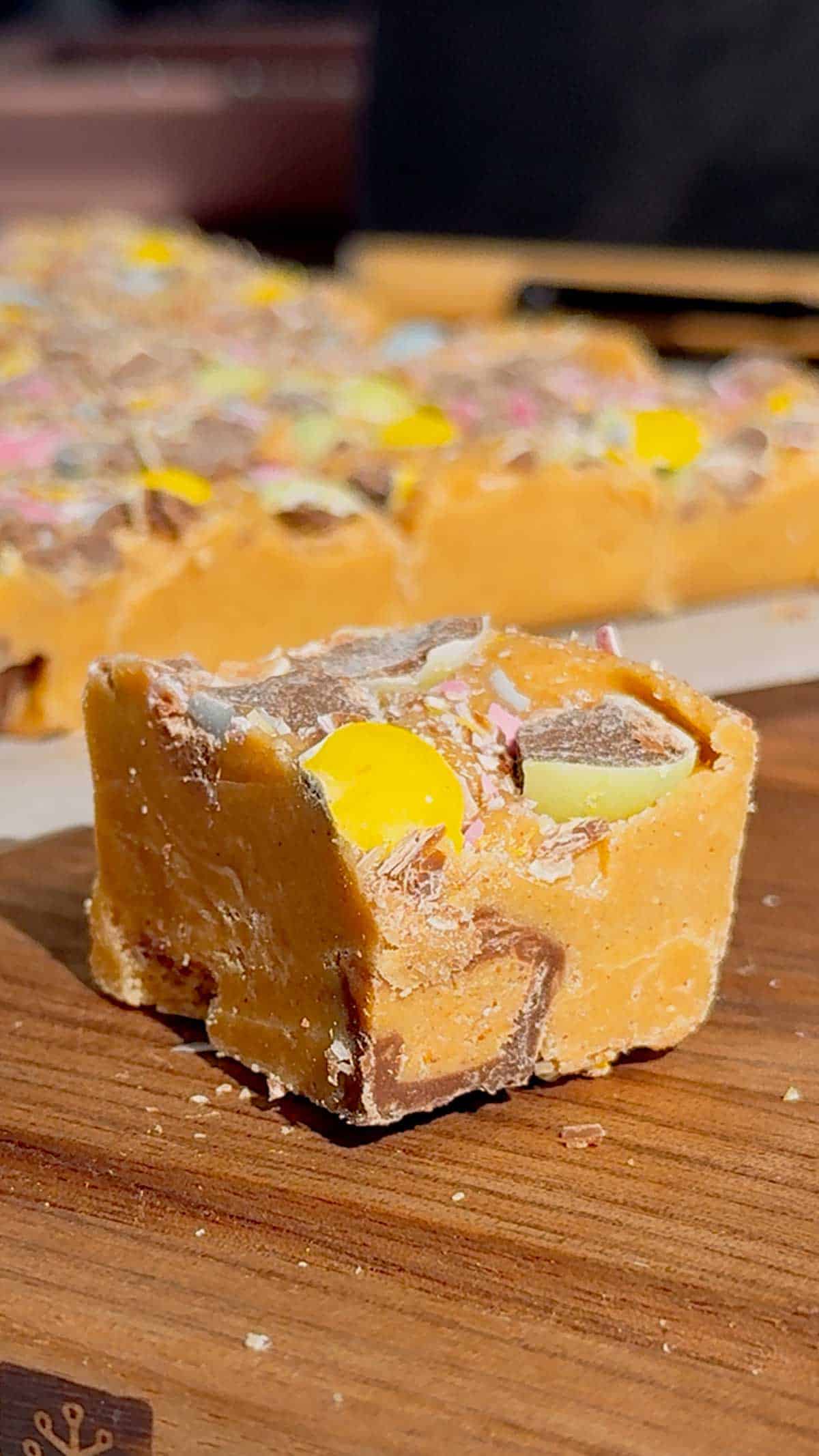 Mini Egg Peanut Butter Cup Fudge is the ultimate easy no bake dessert for Easter and spring parties. This microwave fudge recipe is made with vanilla frosting, peanut butter chips and smooth peanut butter for a rich and creamy texture. Loaded with mini Reese’s peanut butter cups and crushed Cadbury mini eggs, this dessert is perfect for peanut butter lovers. If you’re looking for easy Easter desserts, no bake fudge recipes, simple desserts for a crowd or quick holiday treats, this one is a must try. Great for gifting, dessert trays, potlucks and family gatherings, this sweet treat is colourful, fun and incredibly easy to make. Save this easy fudge recipe for your Easter dessert ideas.