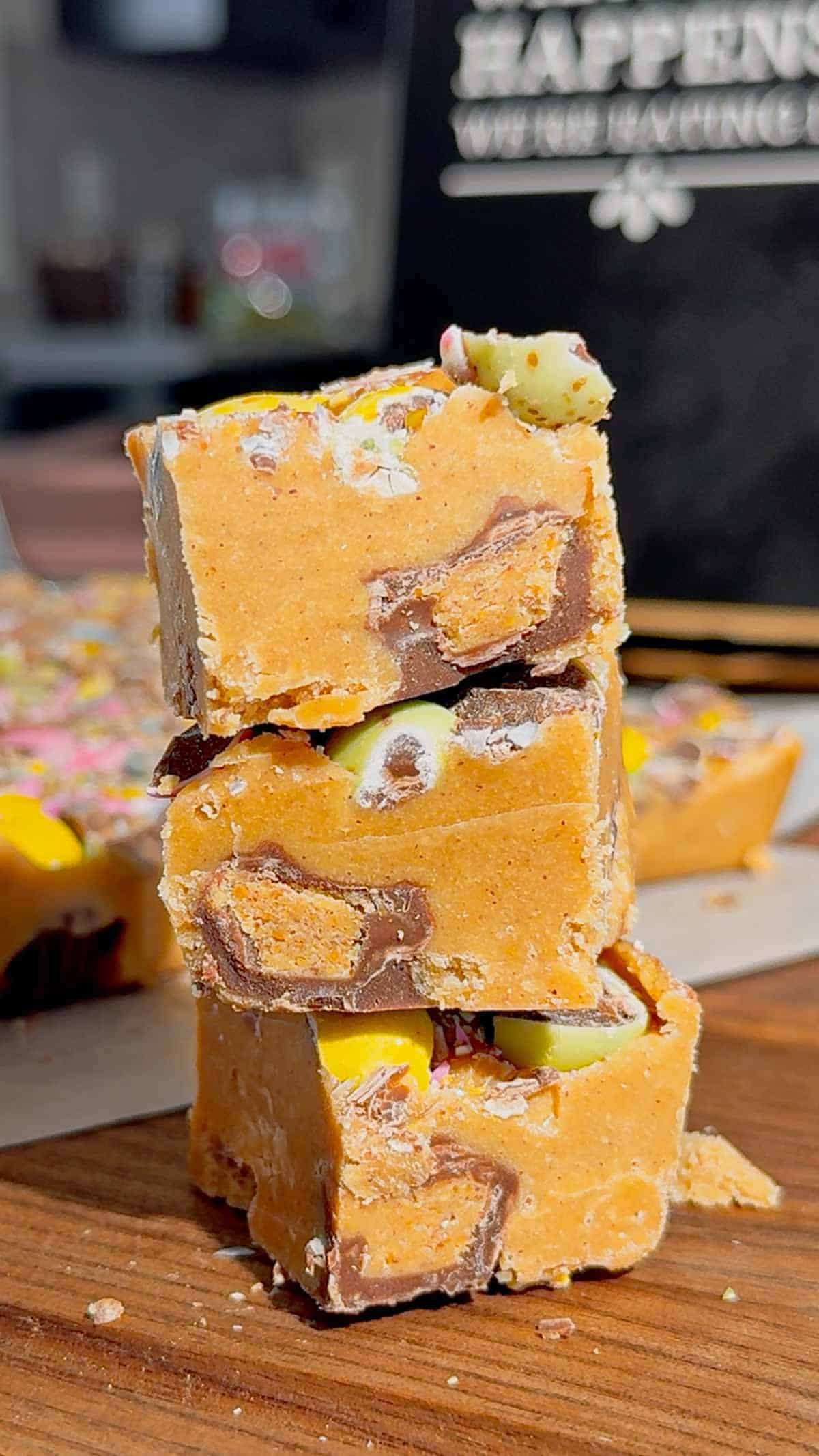 Mini Egg Peanut Butter Cup Fudge is the ultimate easy no bake dessert for Easter and spring parties. This microwave fudge recipe is made with vanilla frosting, peanut butter chips and smooth peanut butter for a rich and creamy texture. Loaded with mini Reese’s peanut butter cups and crushed Cadbury mini eggs, this dessert is perfect for peanut butter lovers. If you’re looking for easy Easter desserts, no bake fudge recipes, simple desserts for a crowd or quick holiday treats, this one is a must try. Great for gifting, dessert trays, potlucks and family gatherings, this sweet treat is colourful, fun and incredibly easy to make. Save this easy fudge recipe for your Easter dessert ideas.