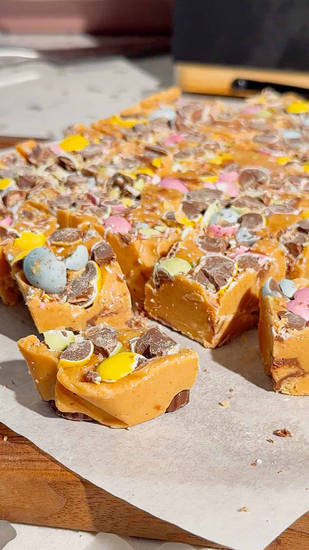 Mini Egg Peanut Butter Cup Fudge is the ultimate easy no bake dessert for Easter and spring parties. This microwave fudge recipe is made with vanilla frosting, peanut butter chips and smooth peanut butter for a rich and creamy texture. Loaded with mini Reese’s peanut butter cups and crushed Cadbury mini eggs, this dessert is perfect for peanut butter lovers. If you’re looking for easy Easter desserts, no bake fudge recipes, simple desserts for a crowd or quick holiday treats, this one is a must try. Great for gifting, dessert trays, potlucks and family gatherings, this sweet treat is colourful, fun and incredibly easy to make. Save this easy fudge recipe for your Easter dessert ideas.