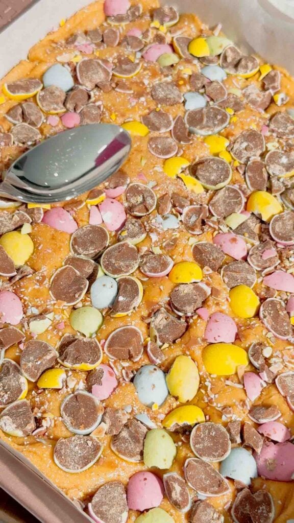 Mini Egg Peanut Butter Cup Fudge is the ultimate easy no bake dessert for Easter and spring parties. This microwave fudge recipe is made with vanilla frosting, peanut butter chips and smooth peanut butter for a rich and creamy texture. Loaded with mini Reese’s peanut butter cups and crushed Cadbury mini eggs, this dessert is perfect for peanut butter lovers. If you’re looking for easy Easter desserts, no bake fudge recipes, simple desserts for a crowd or quick holiday treats, this one is a must try. Great for gifting, dessert trays, potlucks and family gatherings, this sweet treat is colourful, fun and incredibly easy to make. Save this easy fudge recipe for your Easter dessert ideas.