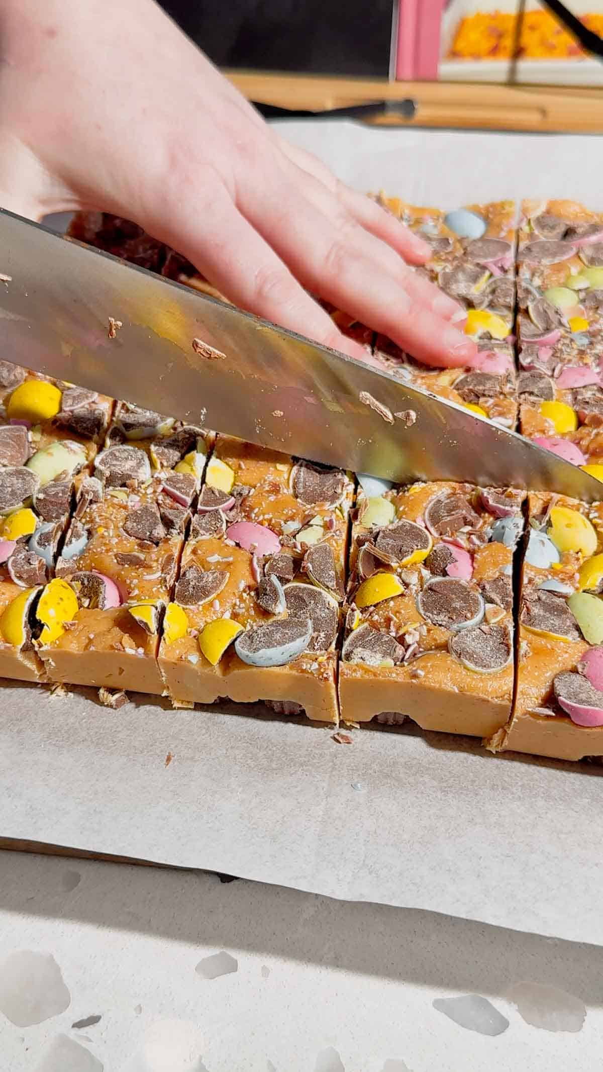 Mini Egg Peanut Butter Cup Fudge is the ultimate easy no bake dessert for Easter and spring parties. This microwave fudge recipe is made with vanilla frosting, peanut butter chips and smooth peanut butter for a rich and creamy texture. Loaded with mini Reese’s peanut butter cups and crushed Cadbury mini eggs, this dessert is perfect for peanut butter lovers. If you’re looking for easy Easter desserts, no bake fudge recipes, simple desserts for a crowd or quick holiday treats, this one is a must try. Great for gifting, dessert trays, potlucks and family gatherings, this sweet treat is colourful, fun and incredibly easy to make. Save this easy fudge recipe for your Easter dessert ideas.