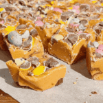 Mini Egg Peanut Butter Cup Fudge is the ultimate easy no bake dessert for Easter and spring parties. This microwave fudge recipe is made with vanilla frosting, peanut butter chips and smooth peanut butter for a rich and creamy texture. Loaded with mini Reese’s peanut butter cups and crushed Cadbury mini eggs, this dessert is perfect for peanut butter lovers. If you’re looking for easy Easter desserts, no bake fudge recipes, simple desserts for a crowd or quick holiday treats, this one is a must try. Great for gifting, dessert trays, potlucks and family gatherings, this sweet treat is colourful, fun and incredibly easy to make. Save this easy fudge recipe for your Easter dessert ideas.