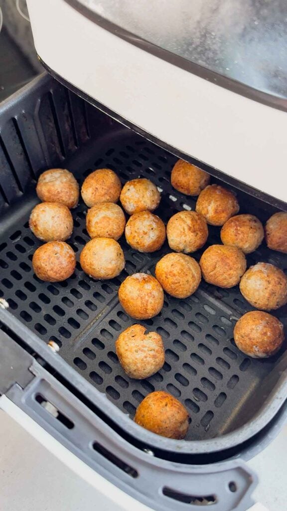 cooked meatballs in an air fryer basket