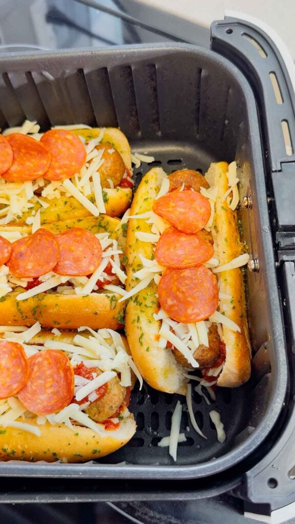 pepperoni and mozzarella cheese on top of meatball subs in an air fryer absket