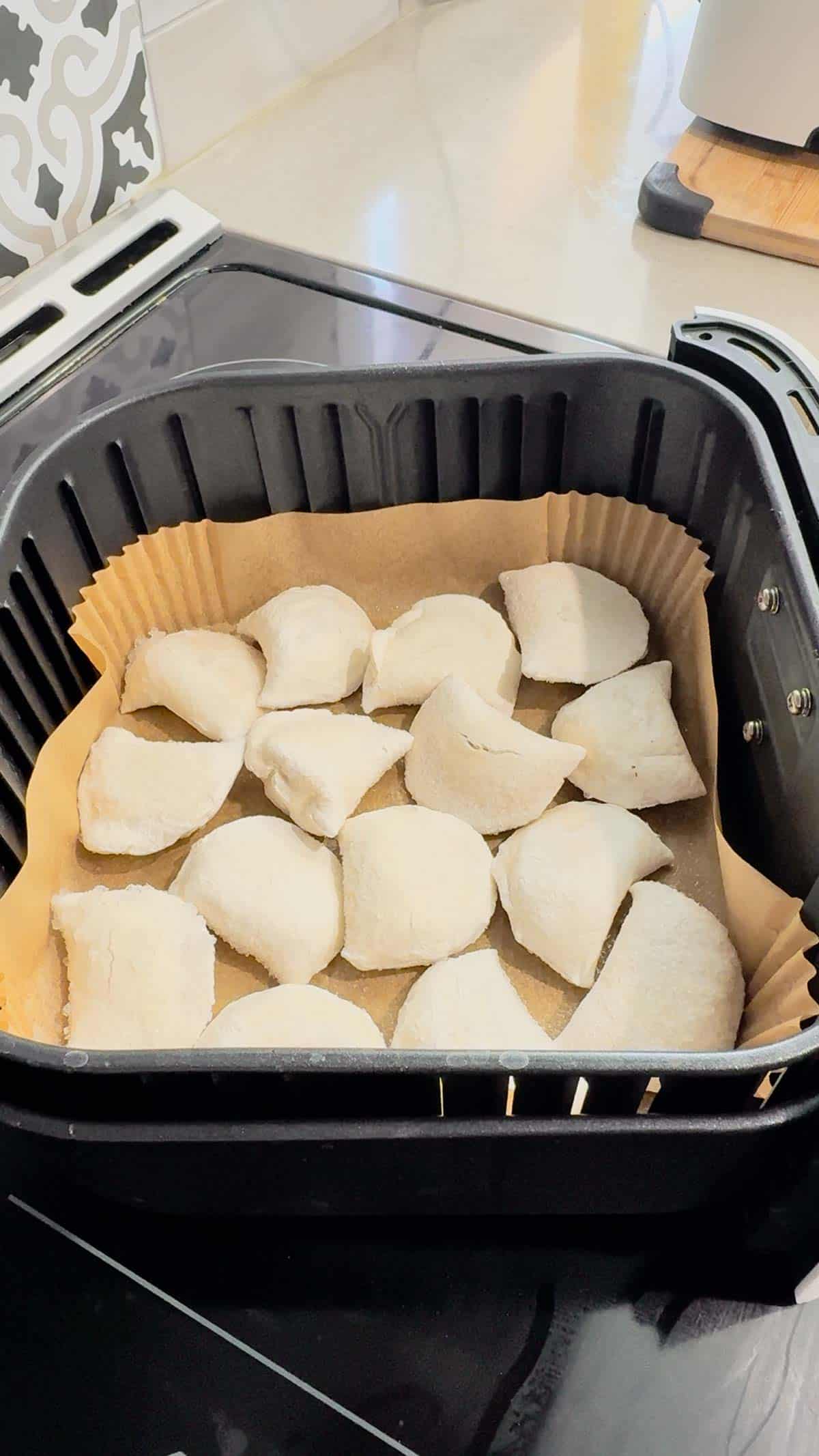 frozen pierogies in a parchment liner in an air fryer basket
