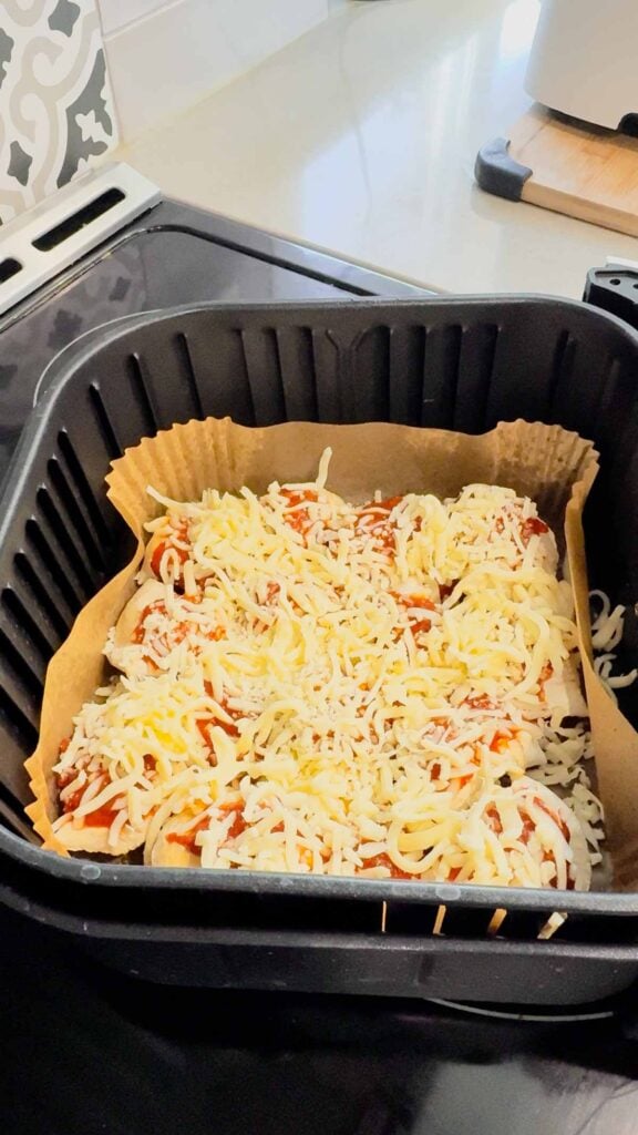 shredded mozzarella and pizza sauce on top of pierogies in an air fryer