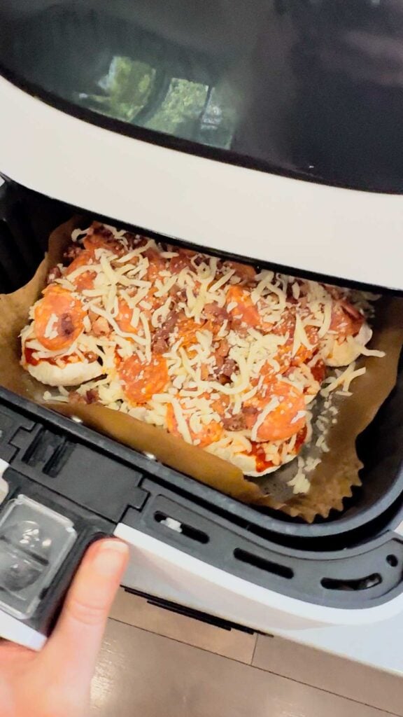 pizza toppings on top of pierogies in an air fryer basket