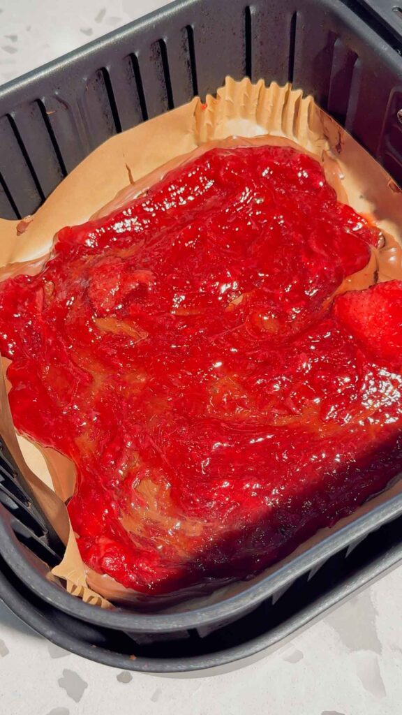 strawberry pie filling spread over Nutella in an air fryer basket liner