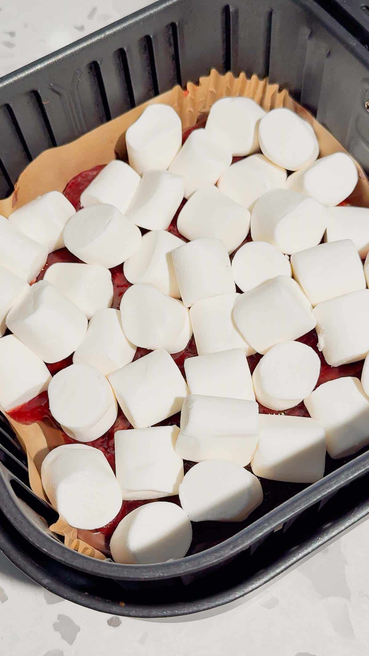 marshmallows on top of Nutella and strawberry pie filling in an air fryer basket liner