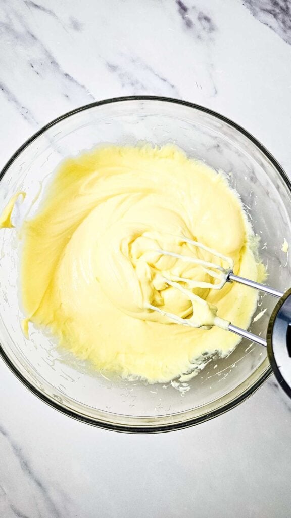 pudding mix and cream cheese being creamed together with an electric mixer