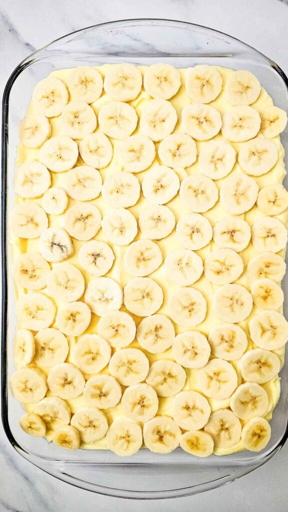 banana slices on top of cream cheese layer on cake